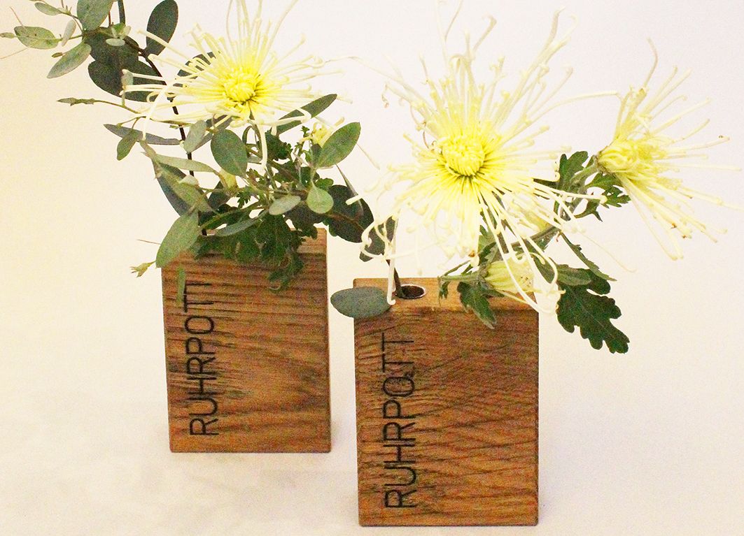 Holzvasen auf rotem Untergrund mit eingefrästen Schriftzügen "Lieblingsmensch" und "Ruhrpott".