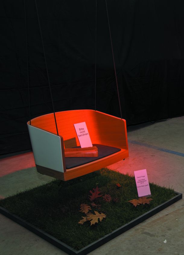 Eine Schaukel, hängend über einem Stück Zierrasen, mit Beleuchtung in Szene gesetzt..