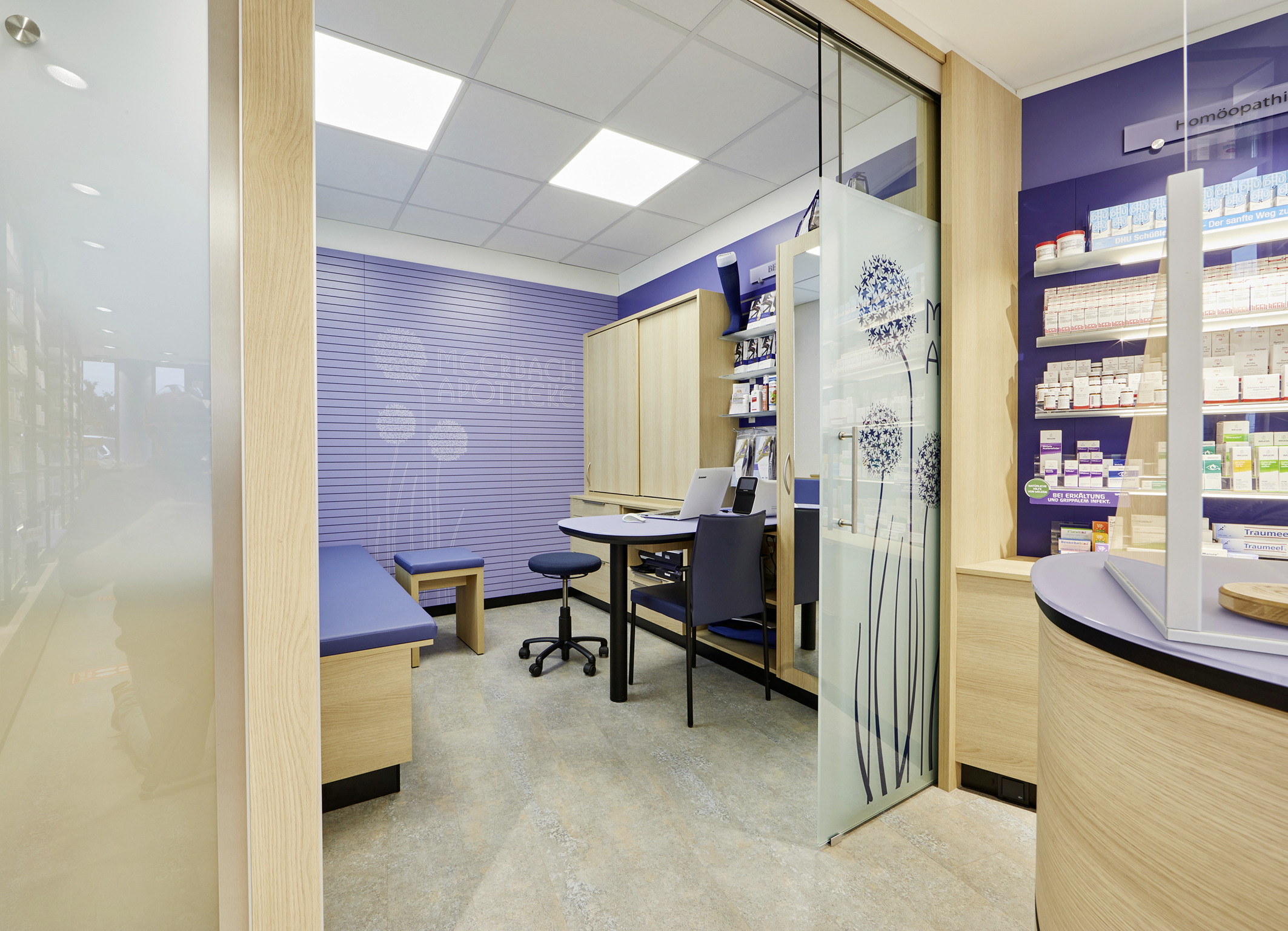 Moderner Beratungsraum mit Holzmöbeln und Glastür mit Pusteblumen-Motiv.