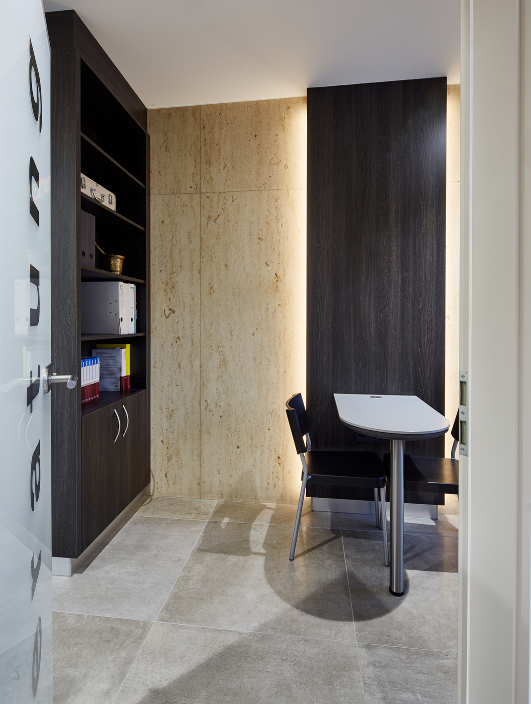 Ein Raum mit zwei Sitzen und einem Tisch sowie Wandschrank mit Akten oder ähnliches.