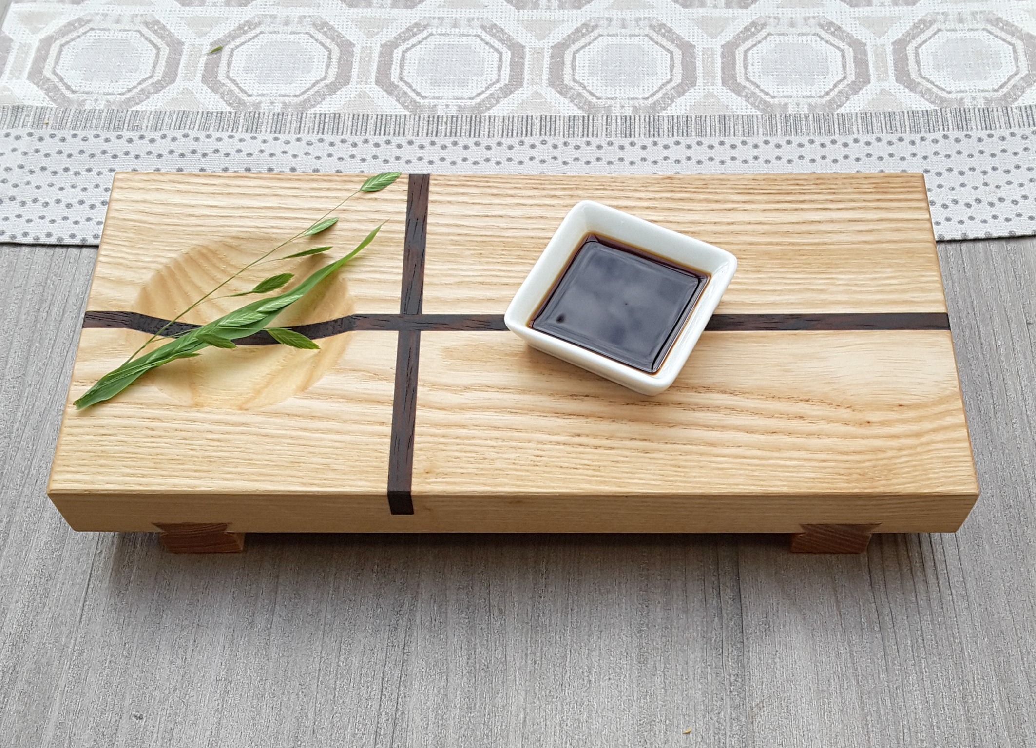 Japanisches Sushi Brett mit Dekozweig und Sojasaucenschale.