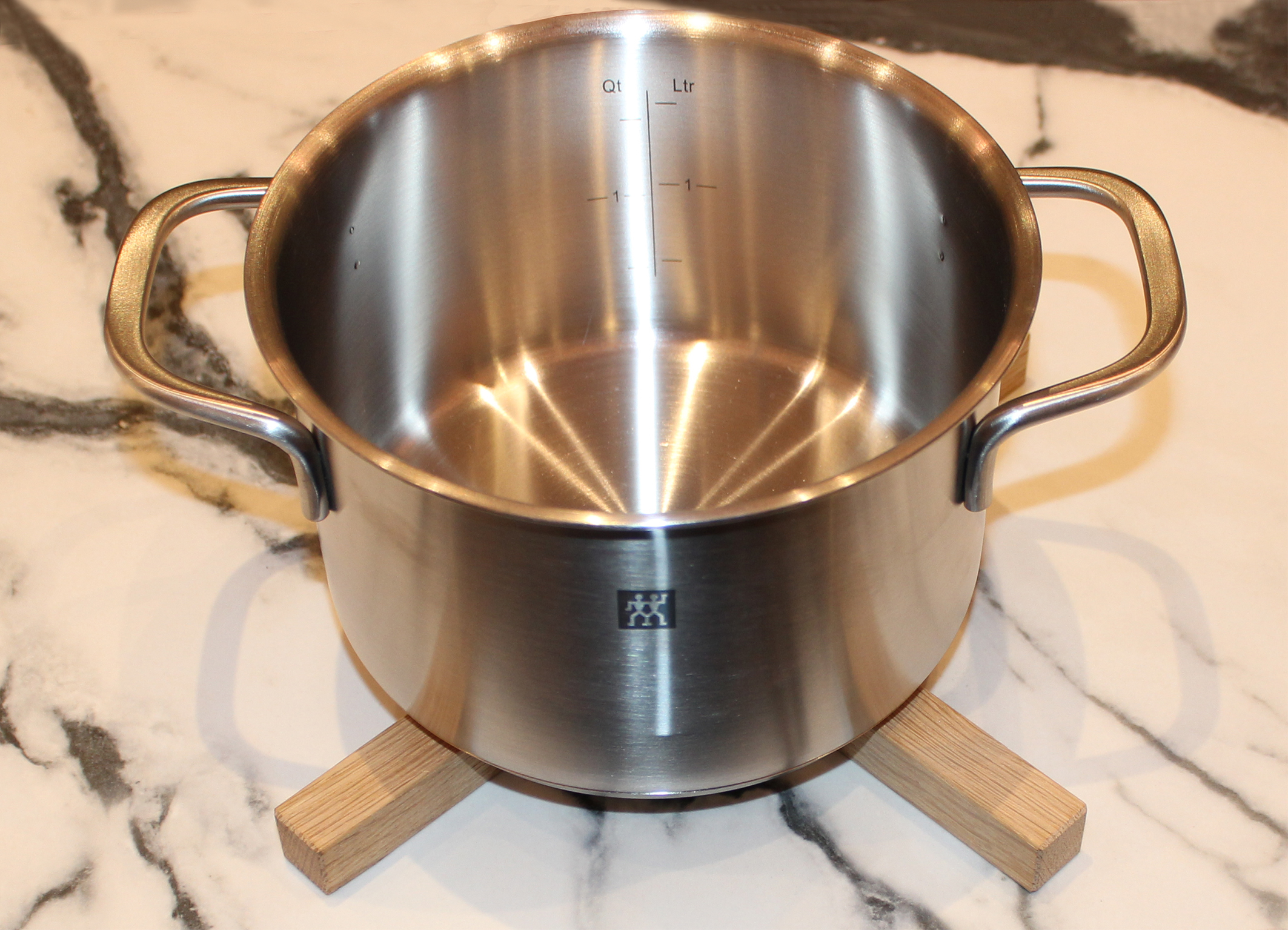 Topfuntersetzer Holzkreuz mit Topf darauf.