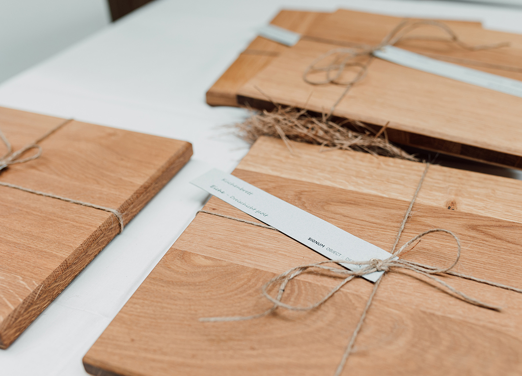 Foto von Holzbrettchen in verschiedenen Holzarten, die mit einer Schleife und einem Etikett versehen sind.