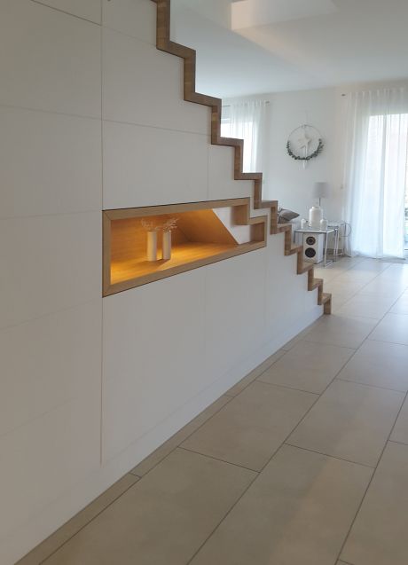 Moderne Treppe mit weißer Verkleidung und integrierter Nische mit Holzrahmen und Beleuchtung in hellem Wohnraum.