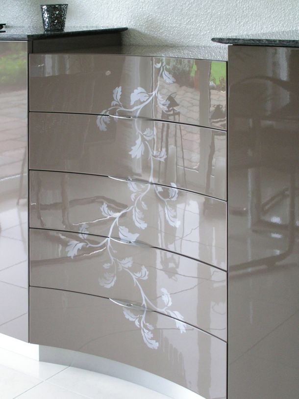 Eine nach innen (konkav) gewölbte Schubladenkommode in Hochglanzlack mit einlackierter Blätterranke.