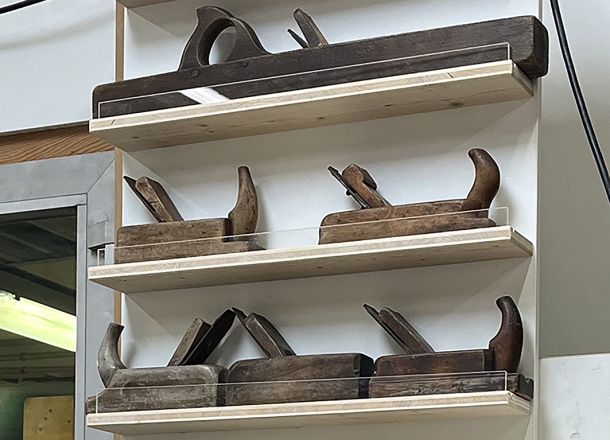 Wandpanel mit historischen Hobeln auf Regalböden.