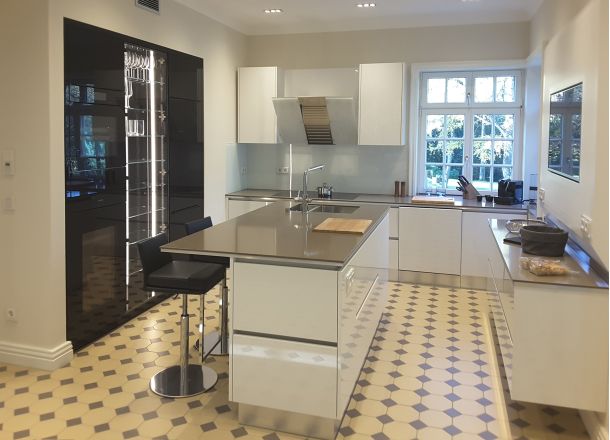 Eine moderne Küche mit Küchenblock in weiß und einer Gerätewand in schwarz mit einem historischen schwarz-gelb karierten Boden.