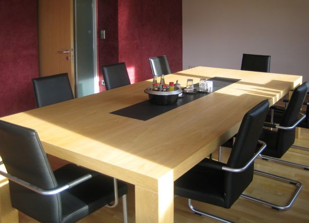 Ein Besprechungsraum mit einem Holztisch und acht Sitzen.