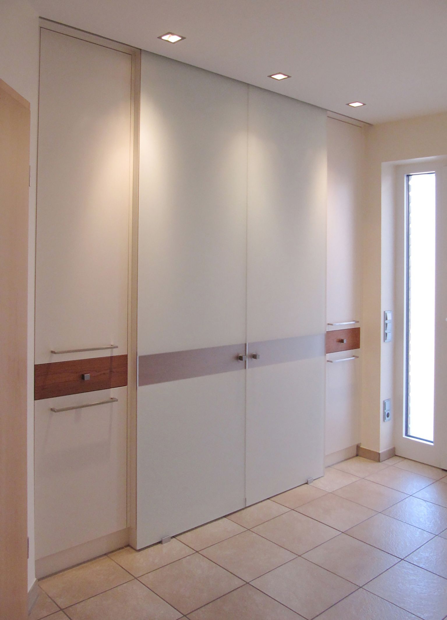 Einbauschrank mit Glasschiebetüren in satiniert und Kirschbaumakzenten.