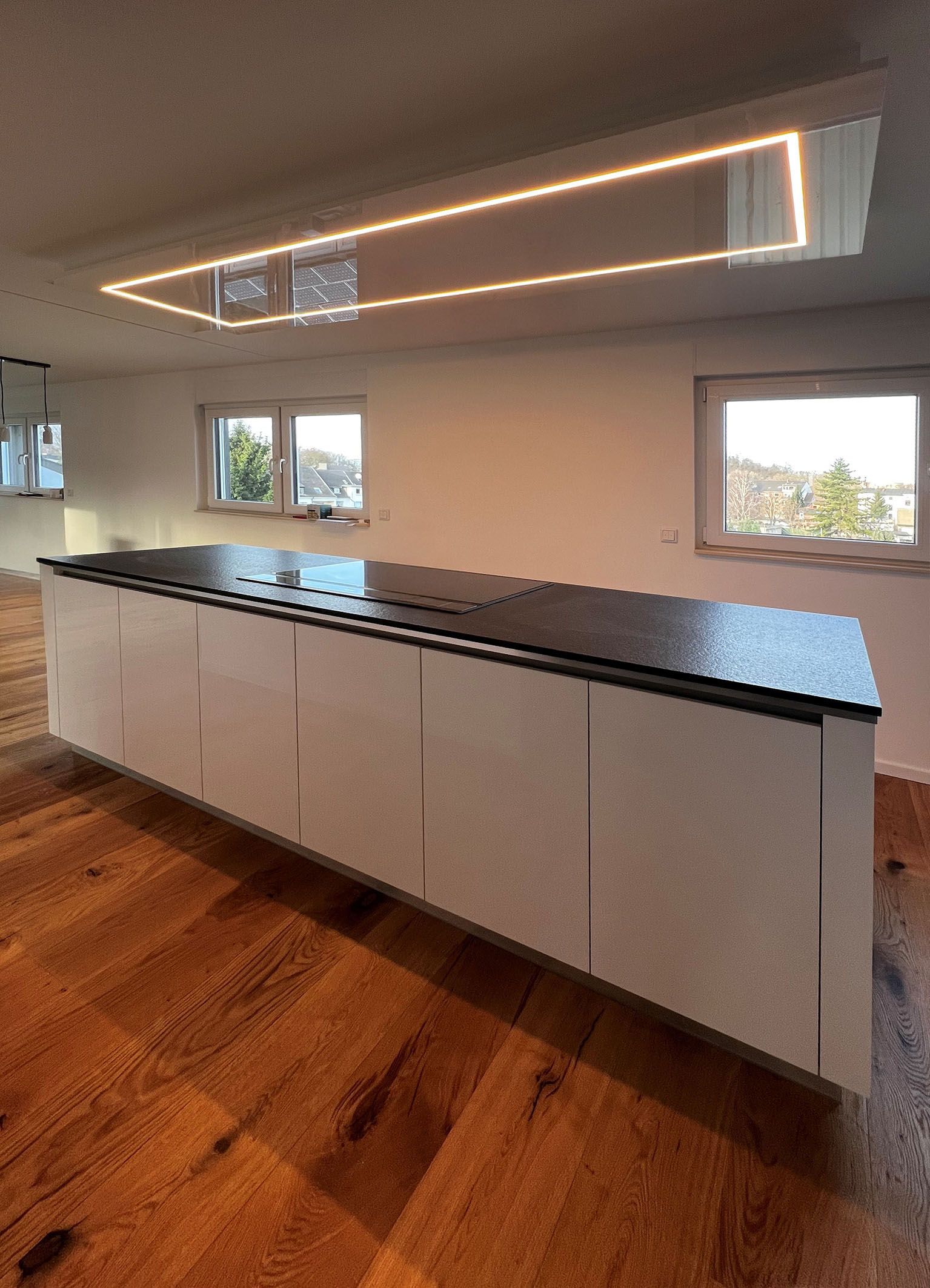 Küchenblock mit grifflosen Fronten in weiß mit Corian Arbeitsplatte in Schieferoptik.