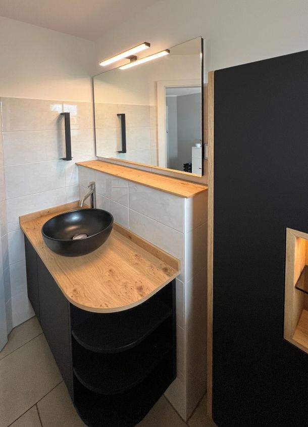 Waschtisch in schwarz mit Deckblatt in Massivholz und Aufsatzwaschbecken in schwarz.