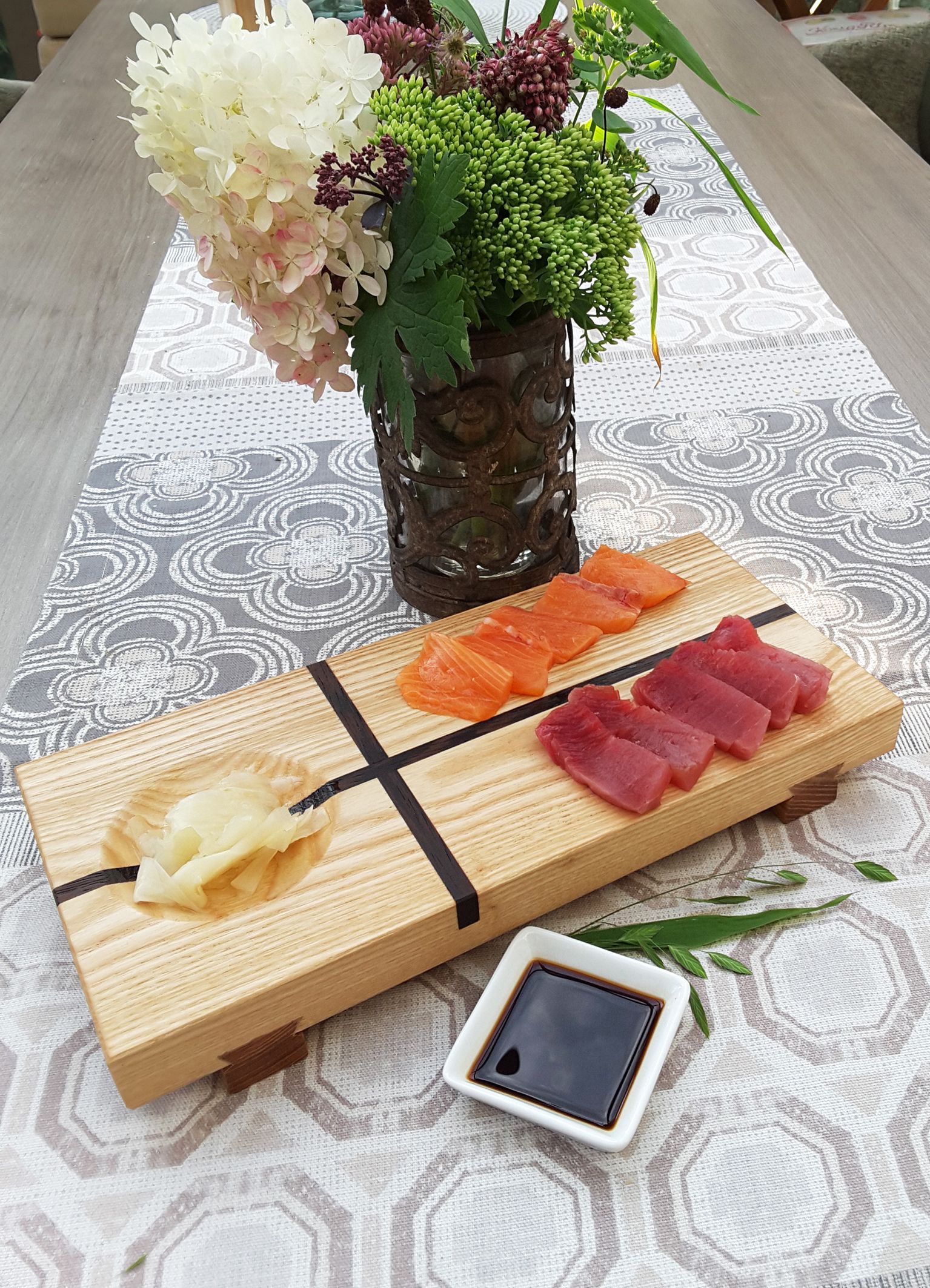 Japanisches Sushi Brett bestückt mit Wasabi, Fischstückchen und einer Schalte Sojasauce.