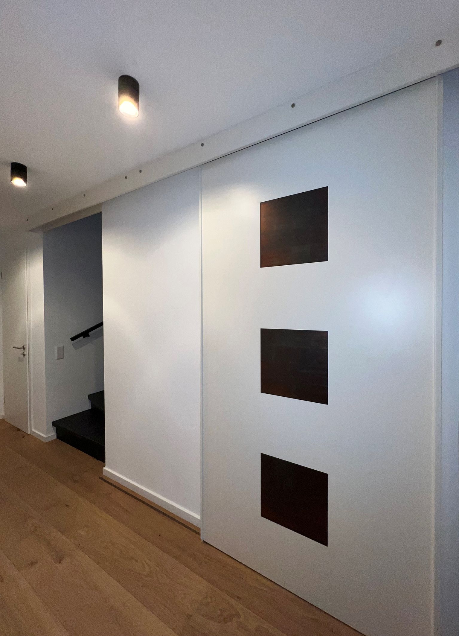 Schiebetür mit eingelassenen Blattsilberfeldern vor Treppenabgang.