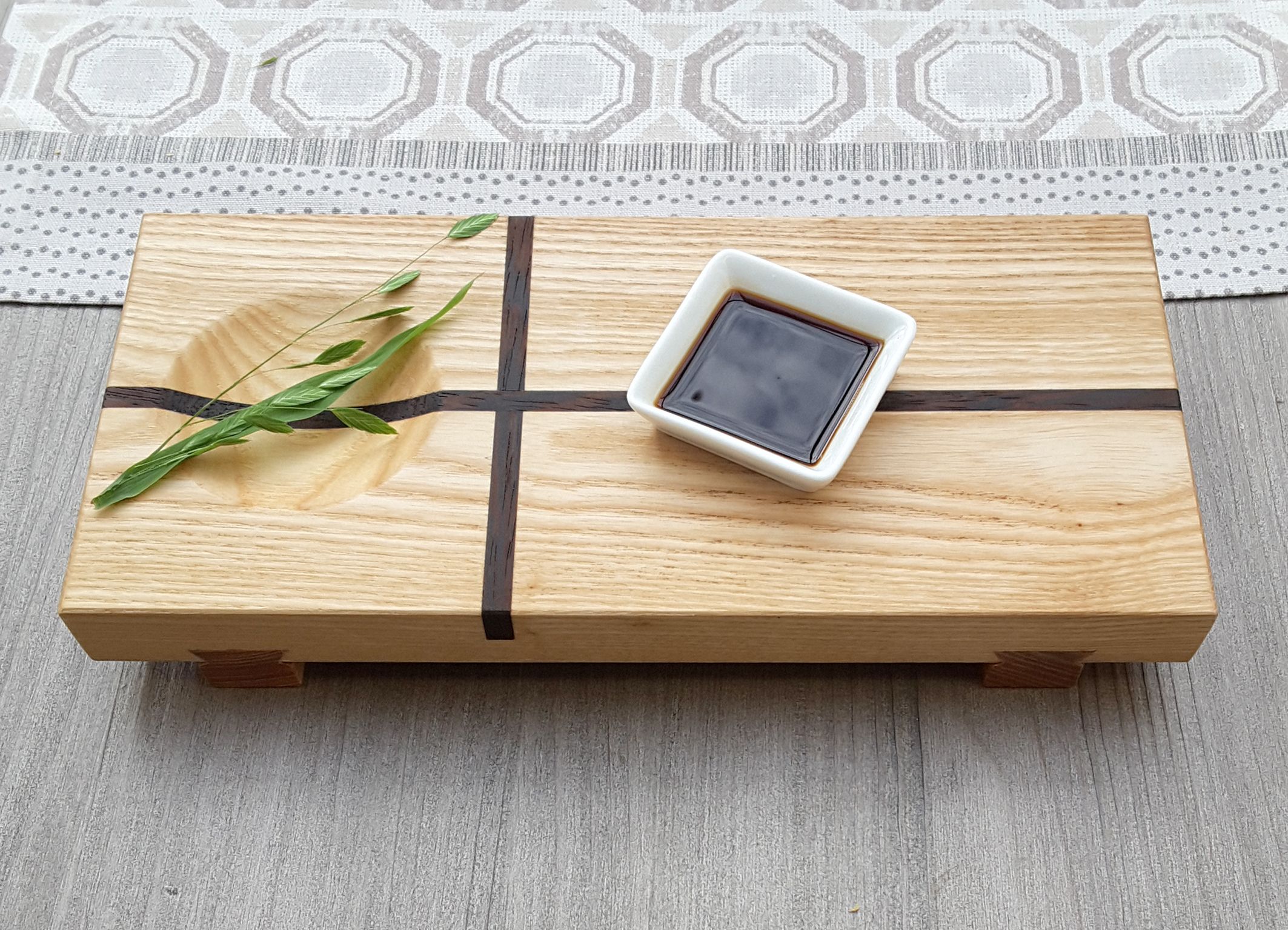 Japanisches Sushi Brett mit Dekozweig und Sojasaucenschale.