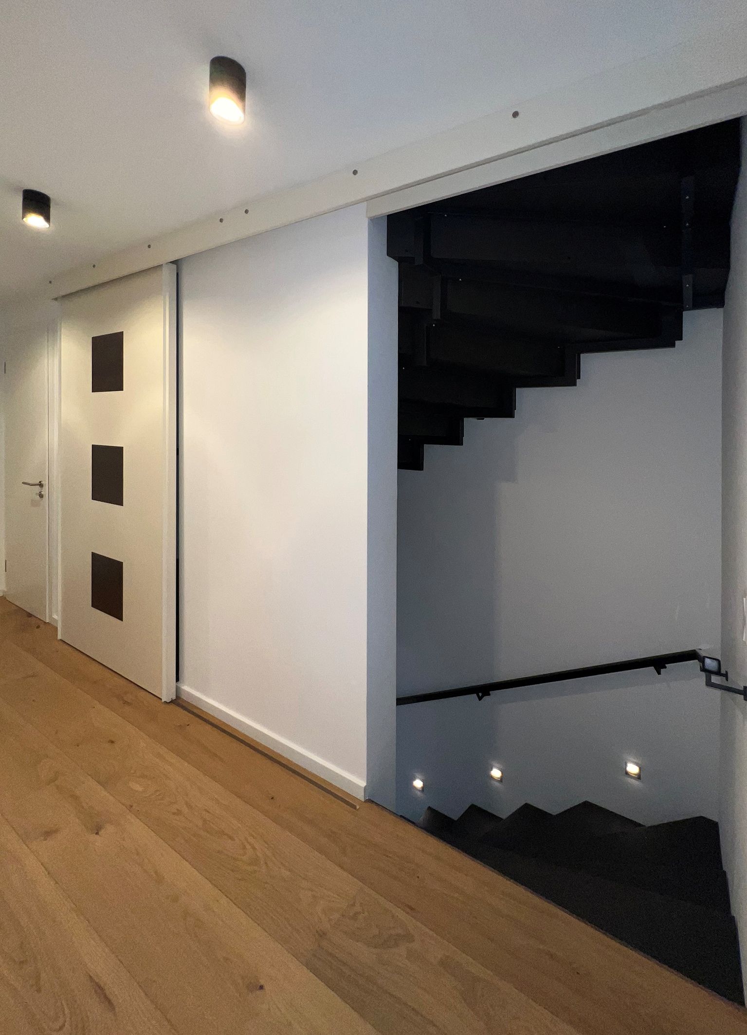 Schiebetür mit eingelassenen Blattsilberfeldern vor Treppenaufgang.