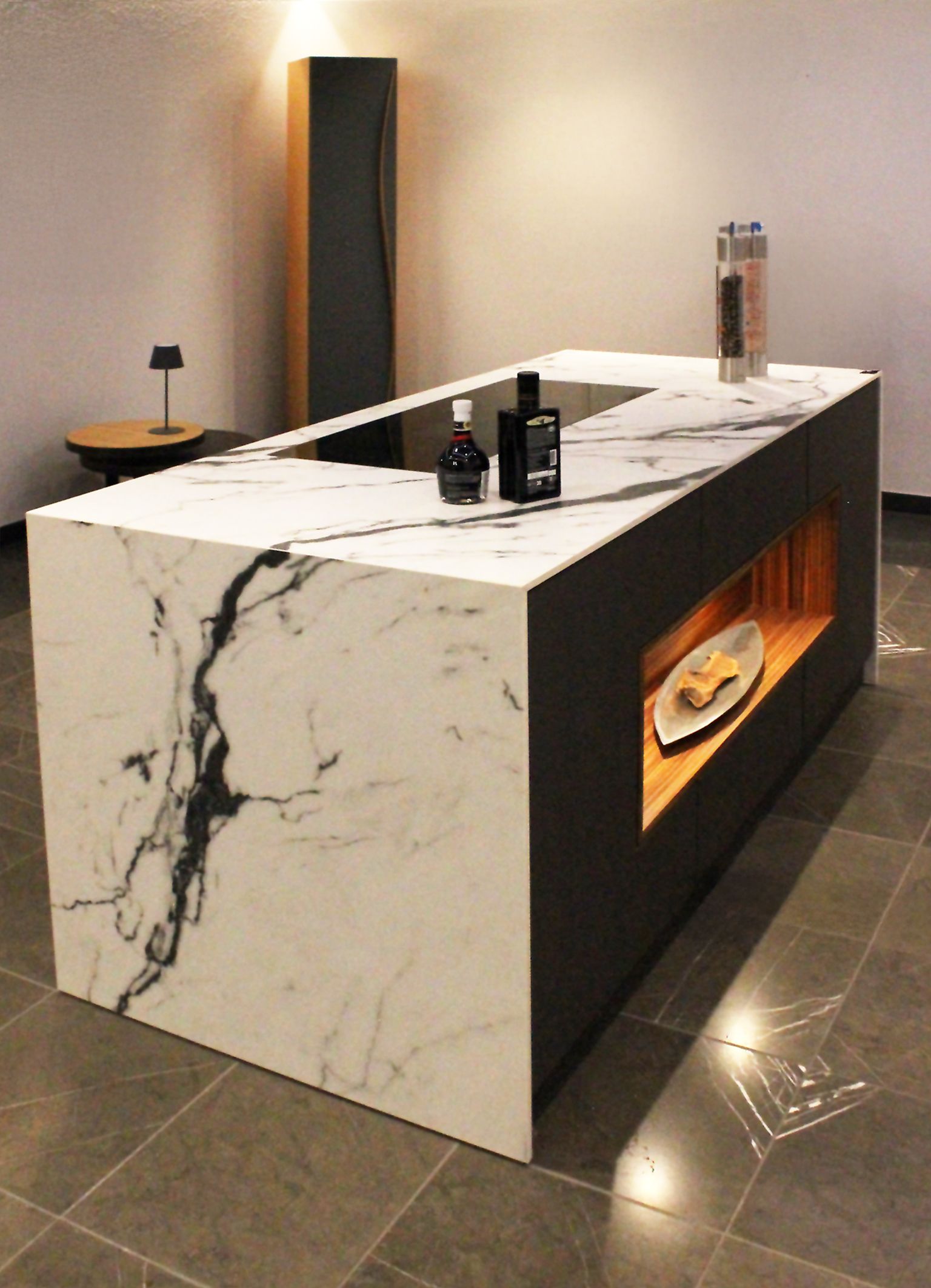 Küchenblock mit Steineinfassung mit auffällig gemaserter Zeichnung, Cerankochfeld und einem beleuchteten Fach