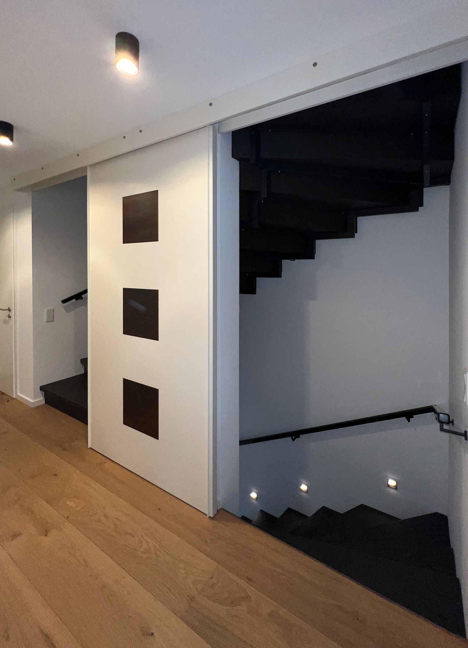 Schiebetür mit eingelassenen Blattsilberfeldern vor Wand Treppenhaus.