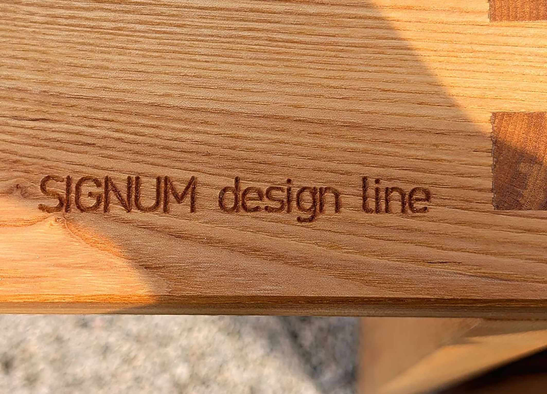 Detail Massivholz mit eingefrästem SIGNUM Schriftzug.